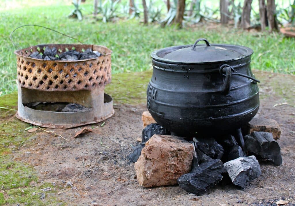 A traditional cooking pot and an mbaula in the background over a circle of fire. A hearth in various forms has provided the principal focal point of a human home.