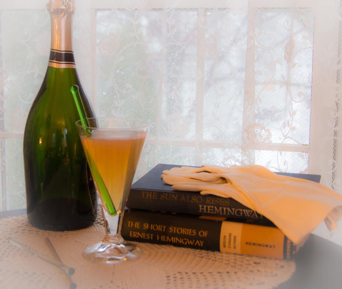 Bottle of absinthe with a glass, beside Hemingway books