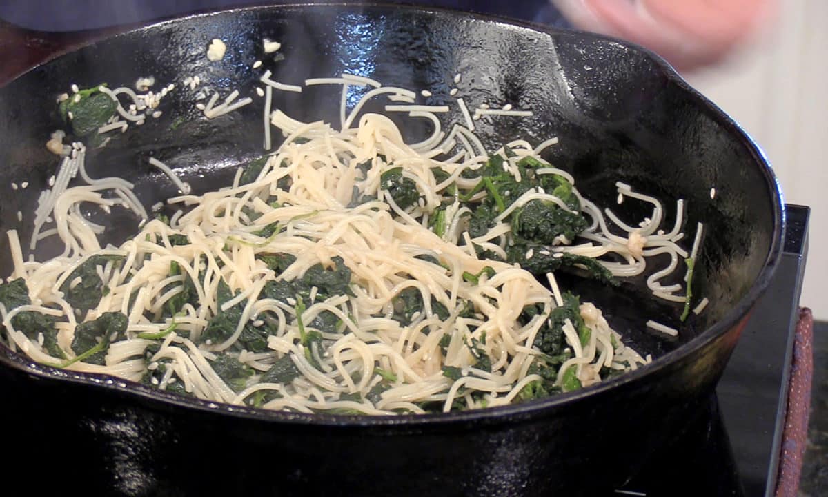 Close-up of a skillet filled with stir-fried nettles and noodles, Asian style.