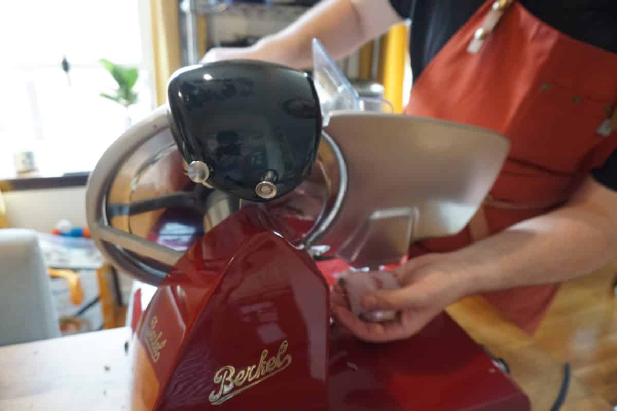 Person using the Berkel Red Line 250 meat slicer to slice meat