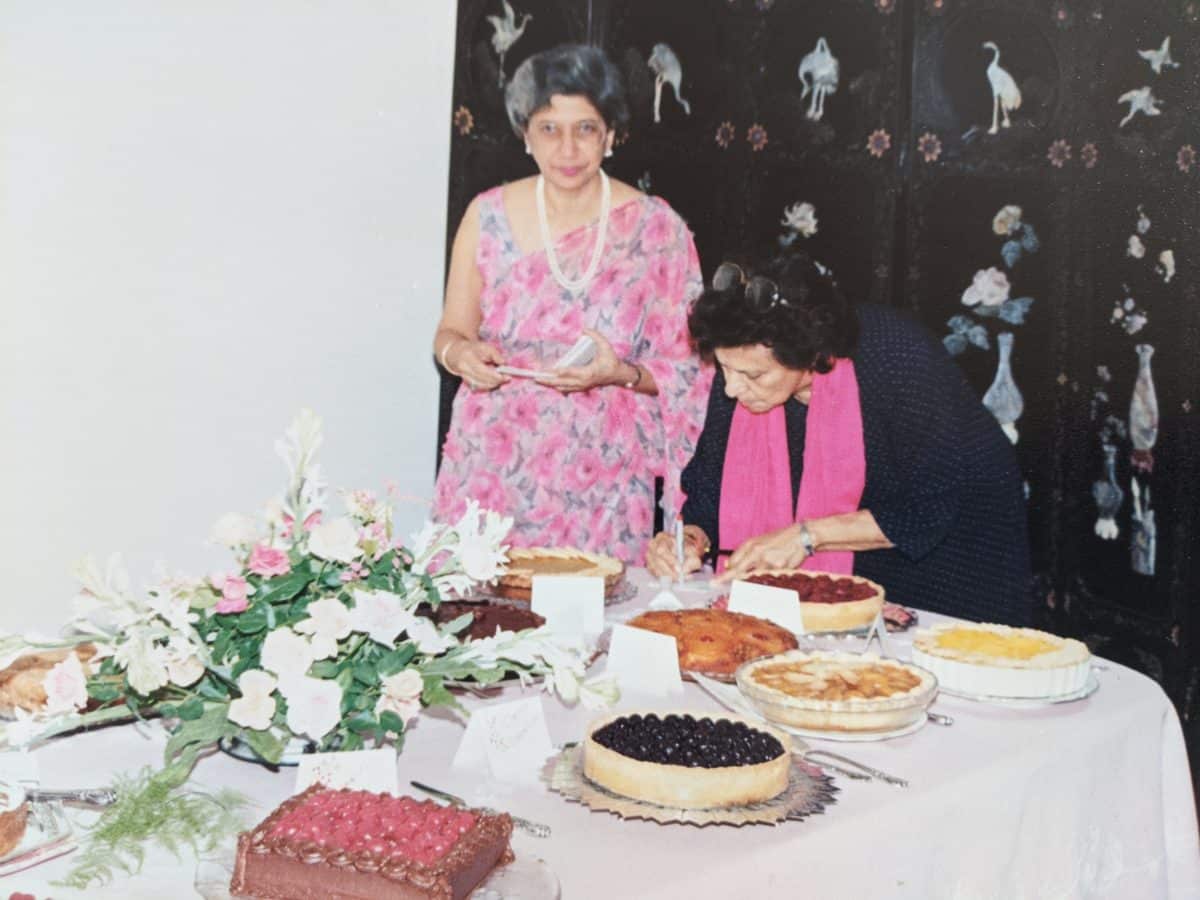 Two women sampling various cakes at an event
