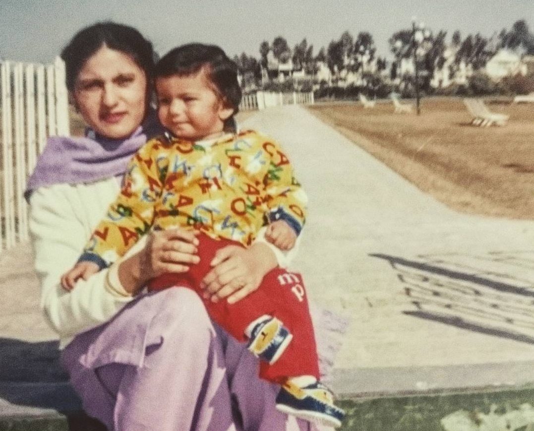 A nostalgic photo of a young boy sitting with his loving mother in an open area, reflecting past memories.