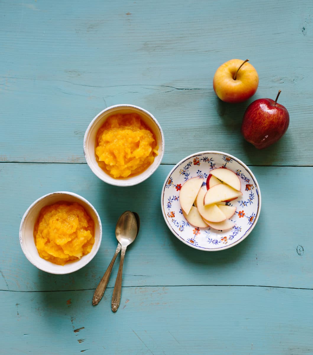 Bowl of saffron-flavored applesauce with apple slices.