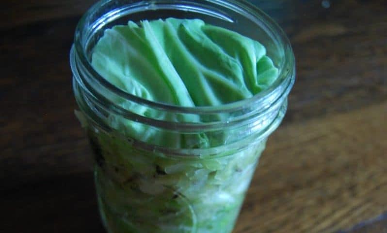Close-up of fresh homemade sauerkraut in a glass jar.