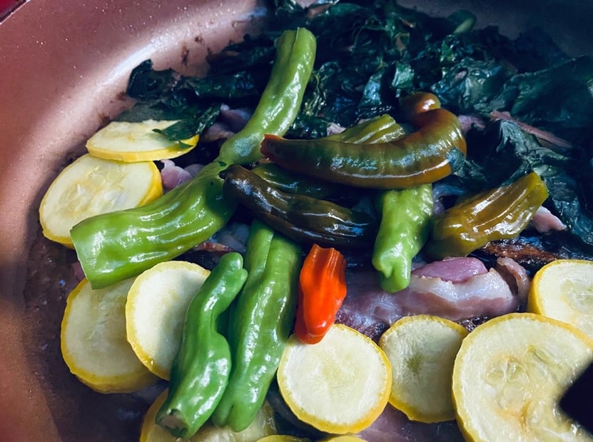 Pan filled with fried Shishito peppers stuffed and accompanied by sliced vegetables.