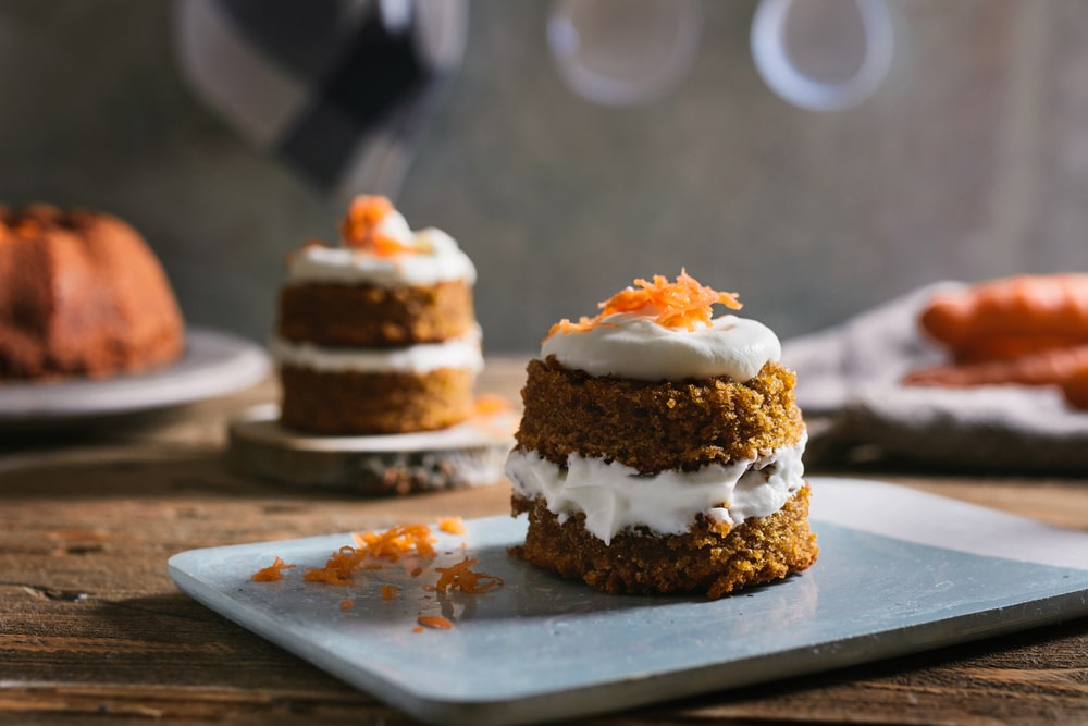 Close-up of a mini carrot cake with cream cheese topping on a blue dish.