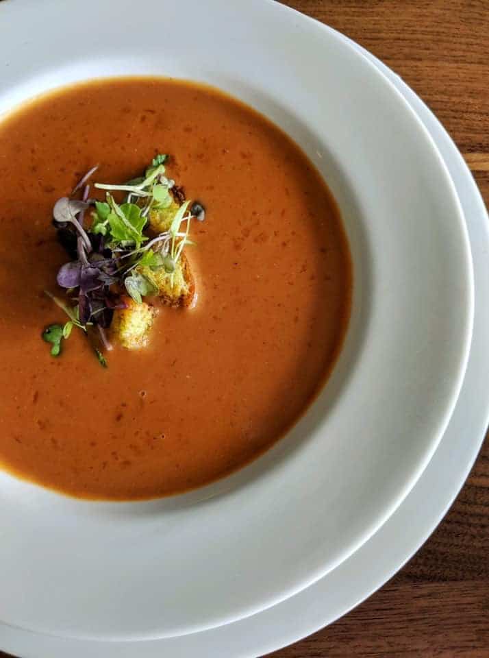 A bowl of creamy lobster bisque garnished with fresh herbs.