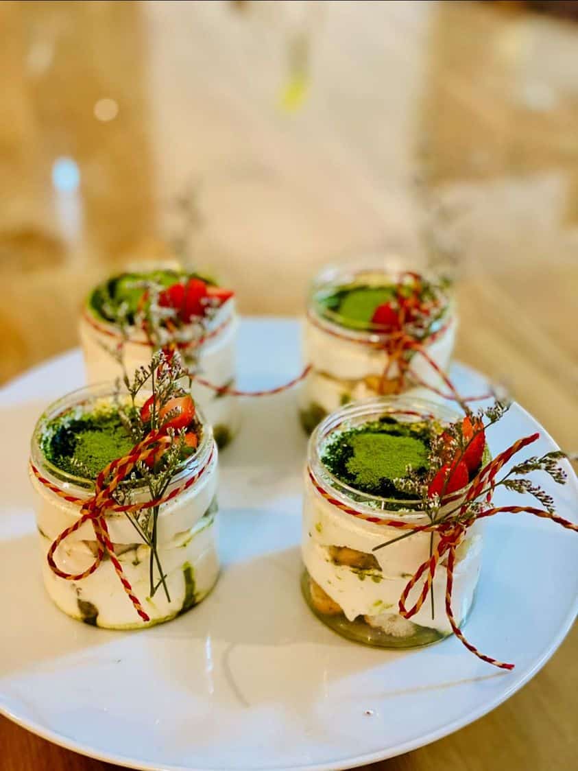 Individual cups of matcha tiramisu garnished with red strands.