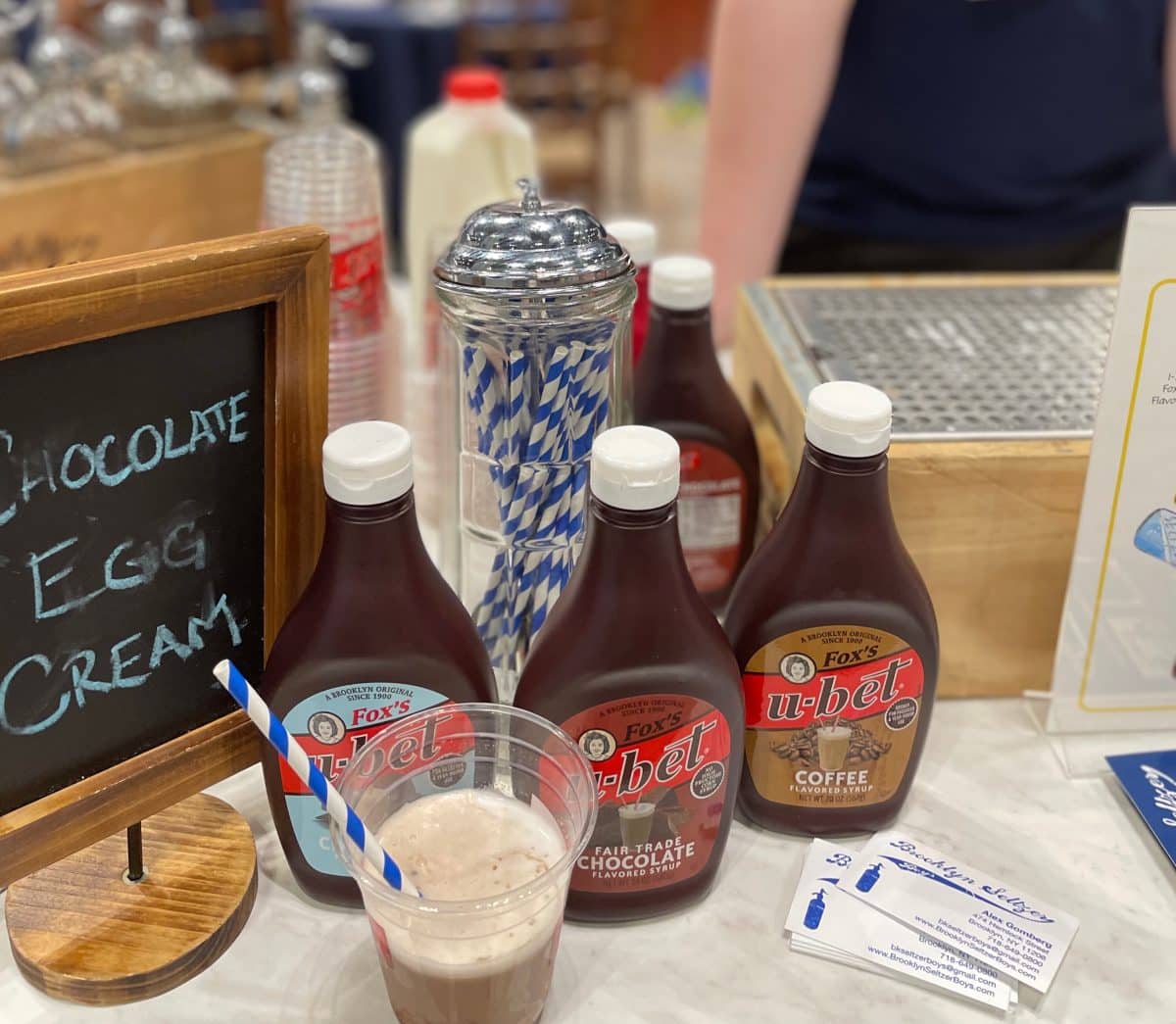 Bottles of chocolate syrup and a glass of chocolate egg cream