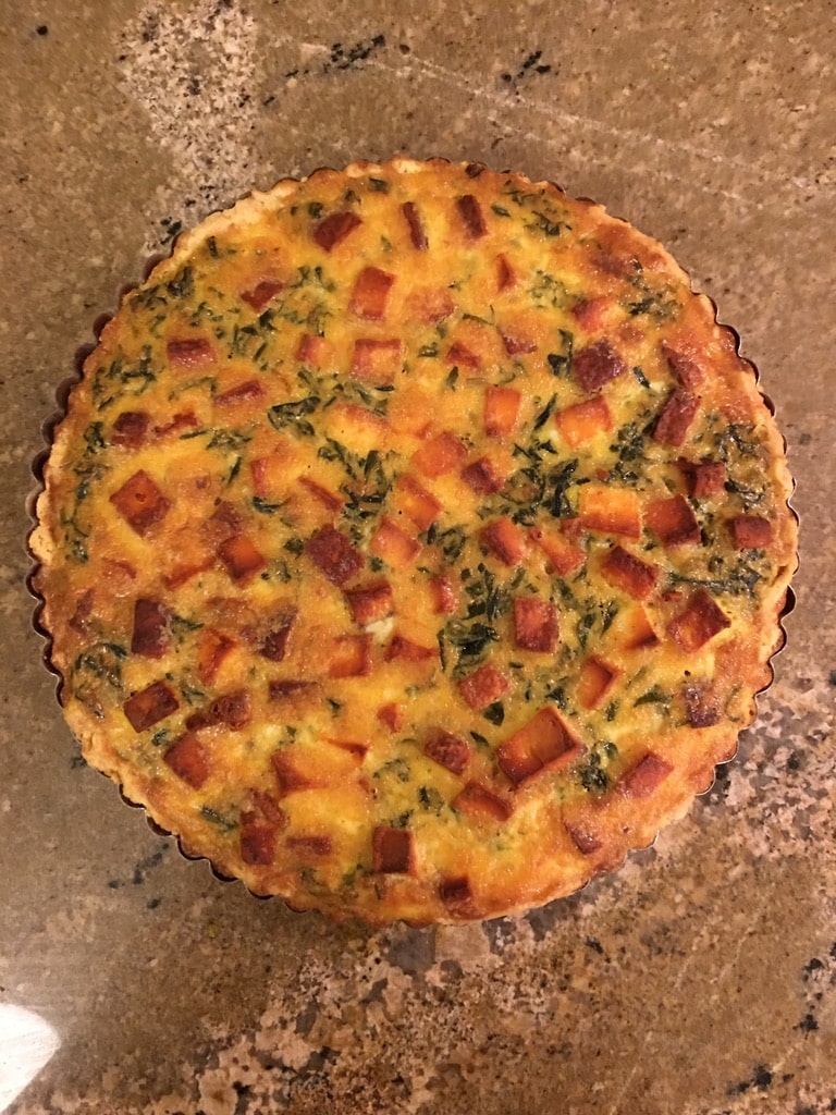 A baked quiche with palak paneer filling showcased in a pie pan.