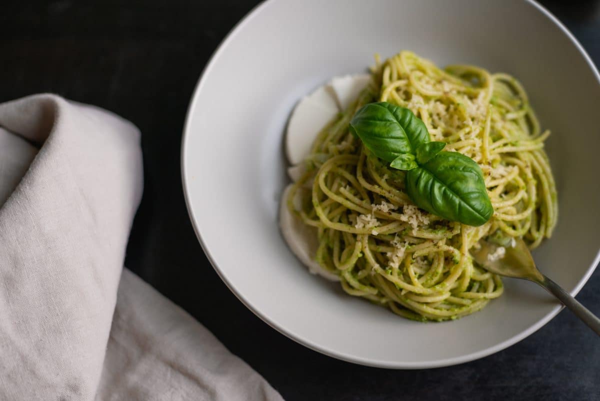 Bowl of spaghetti with Pesto Genovese and fresh basil leaf. Photo by Victoria Alexandrova on Unsplash.