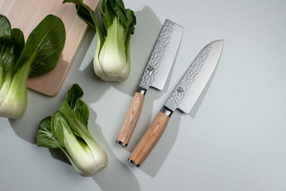 Bok choy next to Japanese chef's knives on a light background