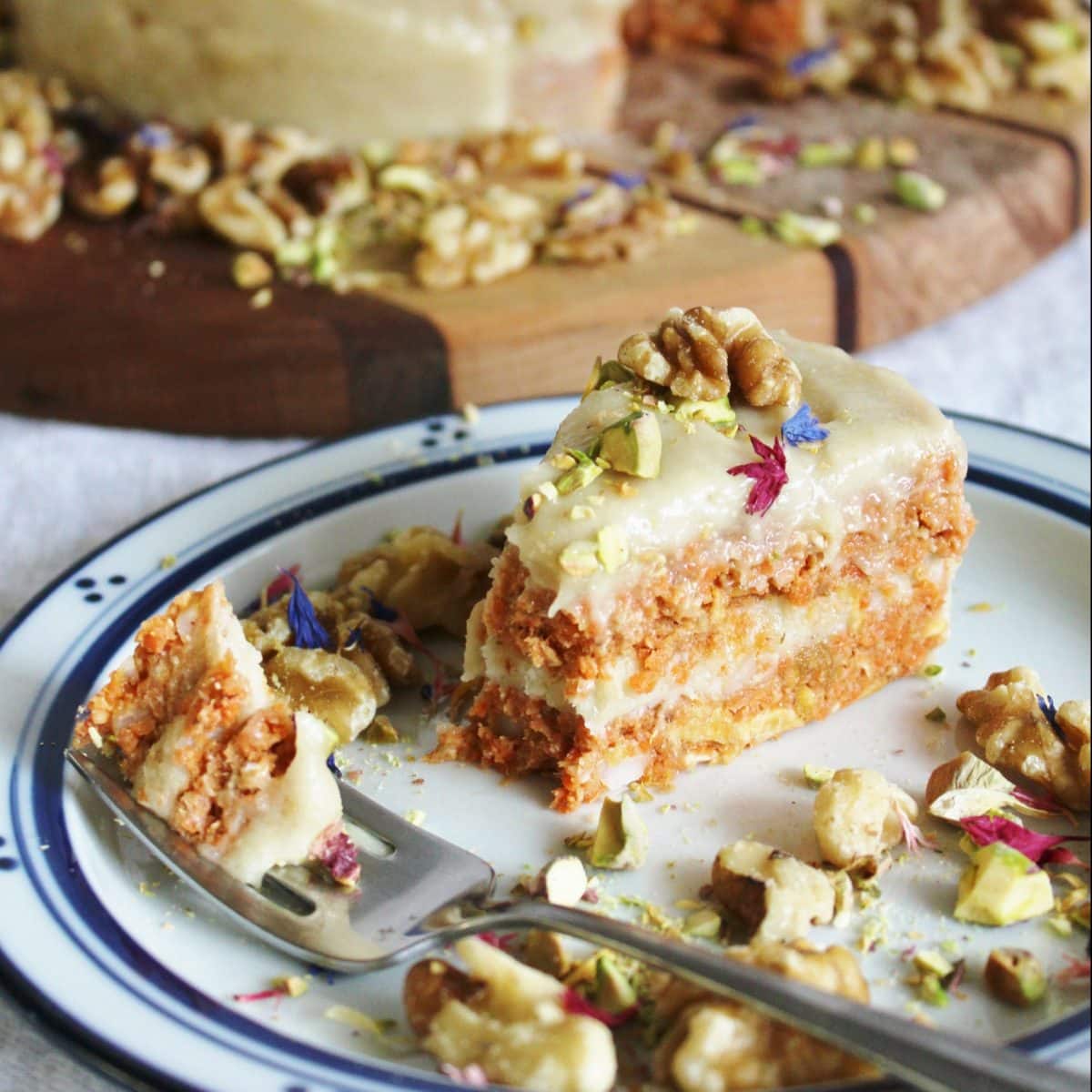 Slice of raw vegan dessert topped with nuts and edible flowers