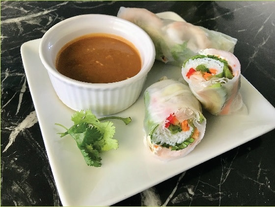 Fresh Vietnamese summer rolls beside a dipping sauce.