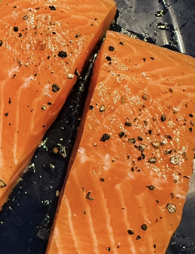 Lightly smoked salmon with salt and pepper, ready to be cooked.