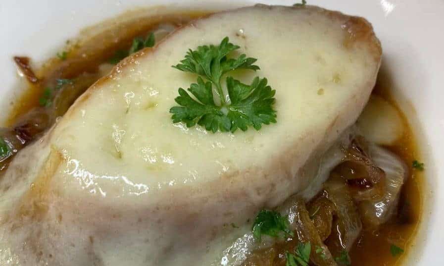 Cooked French onion soup topped with melted cheese and fresh parsley.