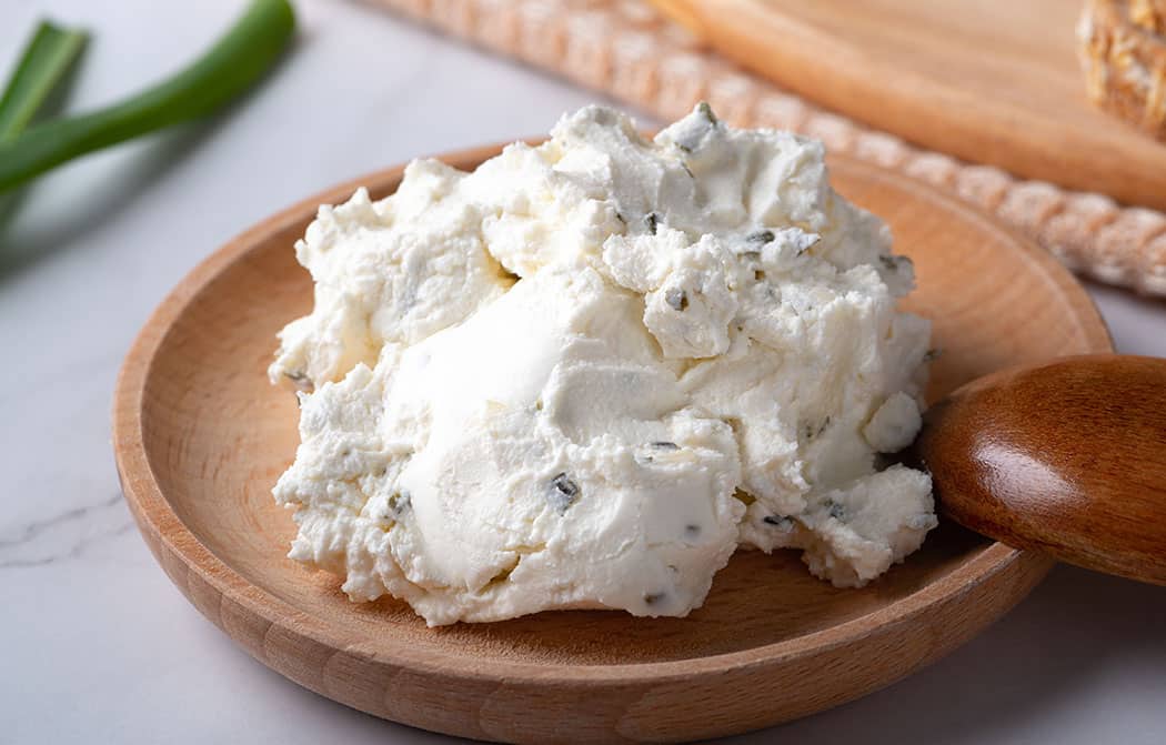 Creamy soft cheese displayed on a round wooden plate.