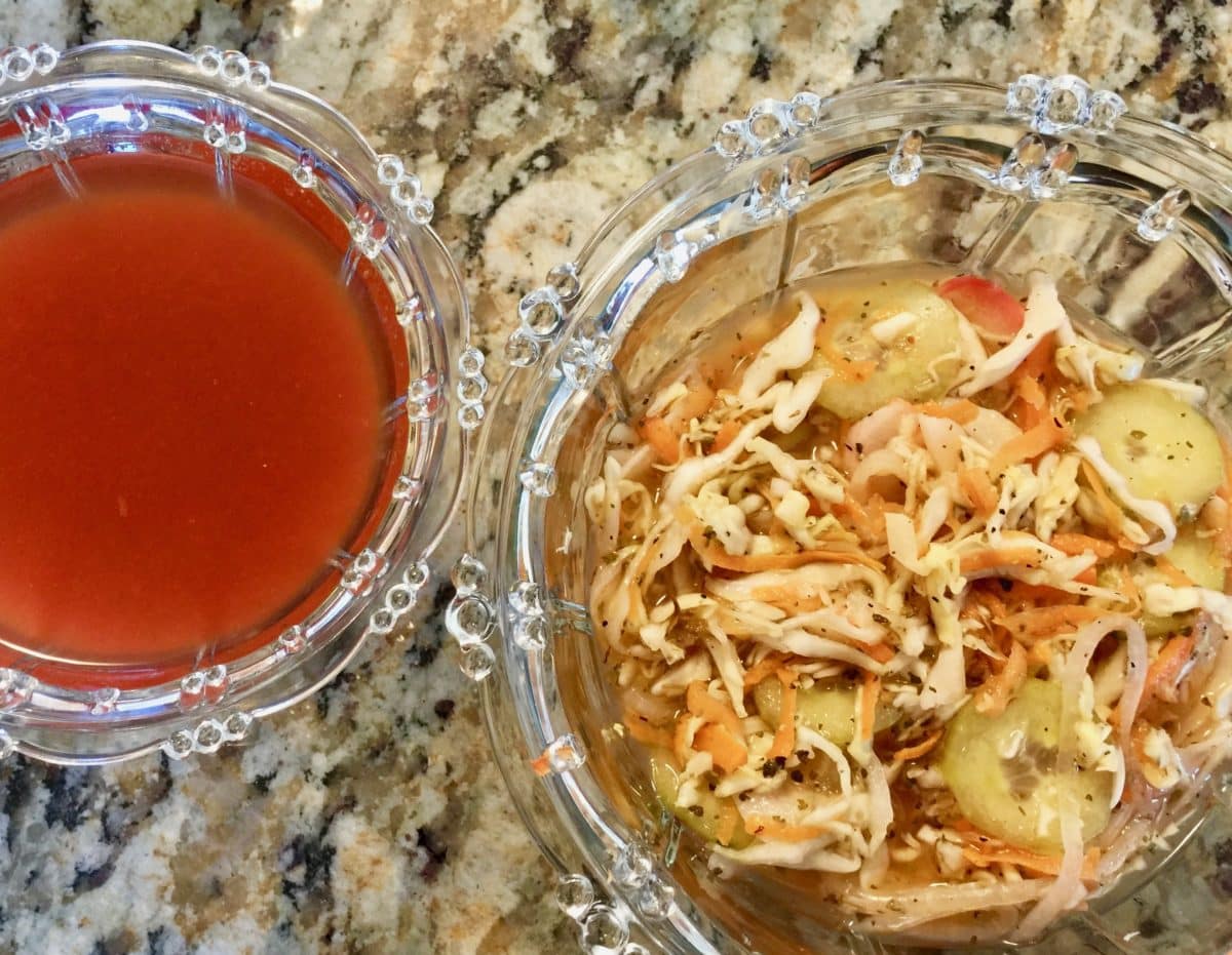 Two glass bowls on granite countertop; one bowl of tomato sauce, one bowl of curtido