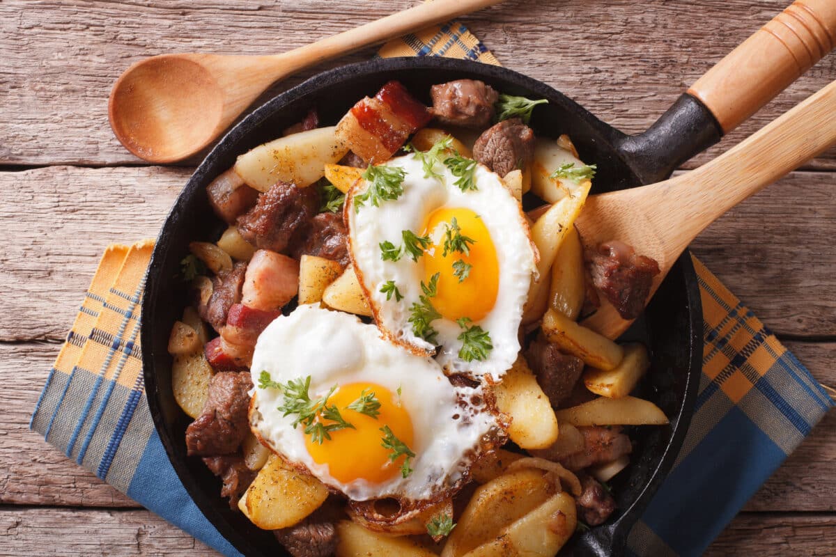 Skillet with turkey red flannel hash with bacon topped with fried eggs