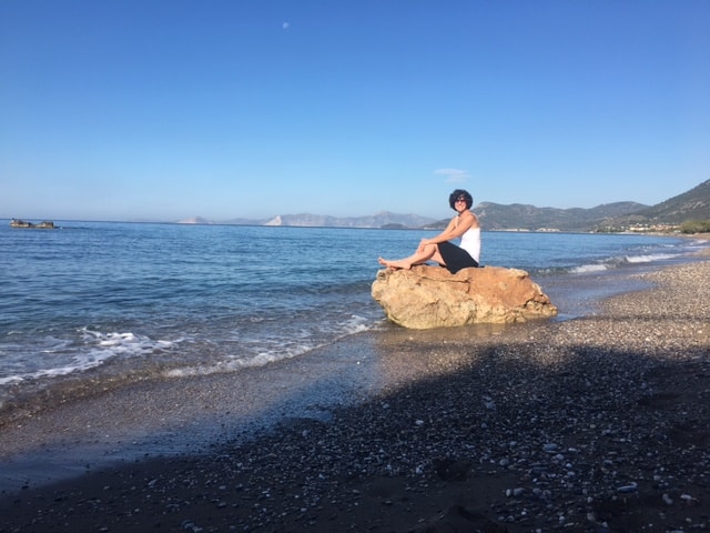 Woman enjoying a serene moment on Votsalakia Beach, Greece.