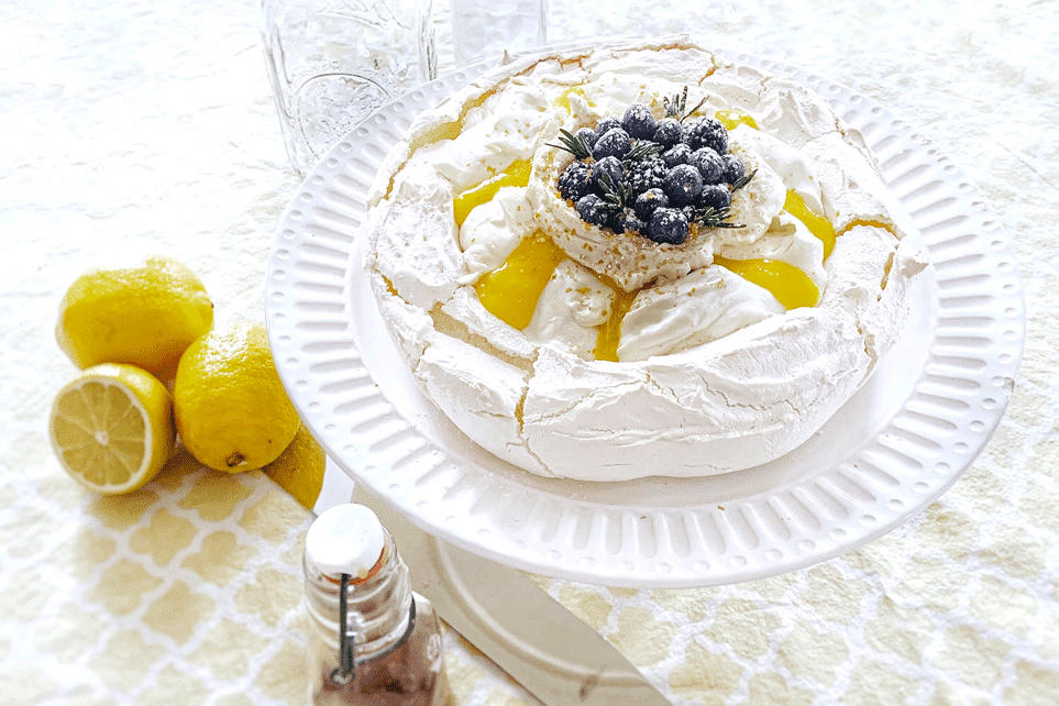 Lemon and blueberry topped pavlova on a white plate.